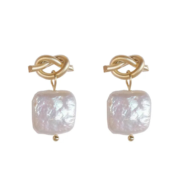 Product shot of Bound in Grace Earrings showing gold knot studs and iridescent square pearls, ideal for modern feminine style.