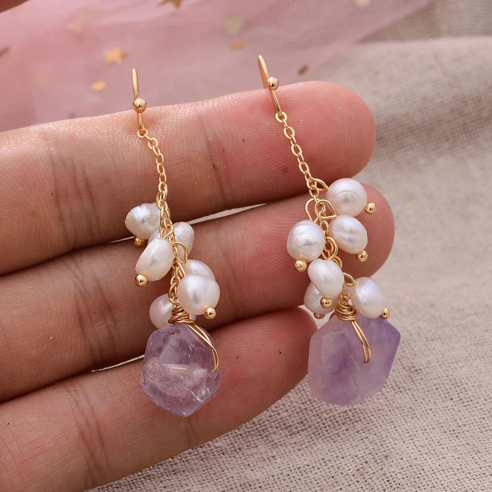 Twilight Bloom Earrings featuring freshwater pearls and irregular amethyst stones on 14K gold-filled hooks, shown on hand for scale.