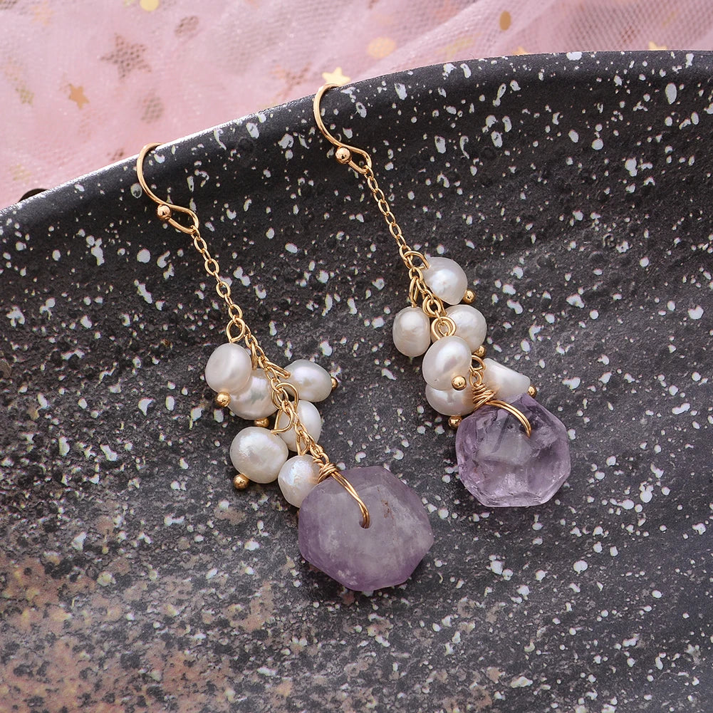 Twilight Bloom Earrings with amethyst and pearls displayed on black speckled surface, perfect for elegant occasions.