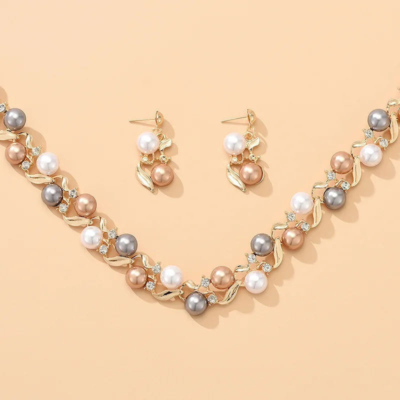 Royal Serenity Set for Women featuring a pearl necklace and earrings with gold leaf accents, arranged neatly on a peach background.
