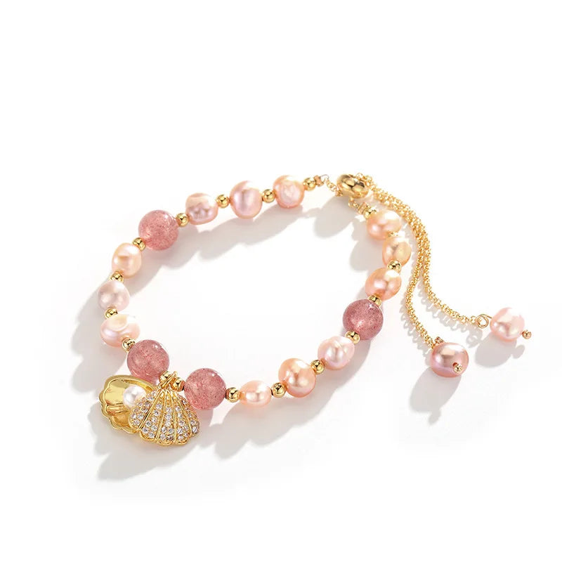 Flat-lay of Pink Whisper Shell Bracelet with pink pearls, strawberry quartz, and gold shell charm on a white background.