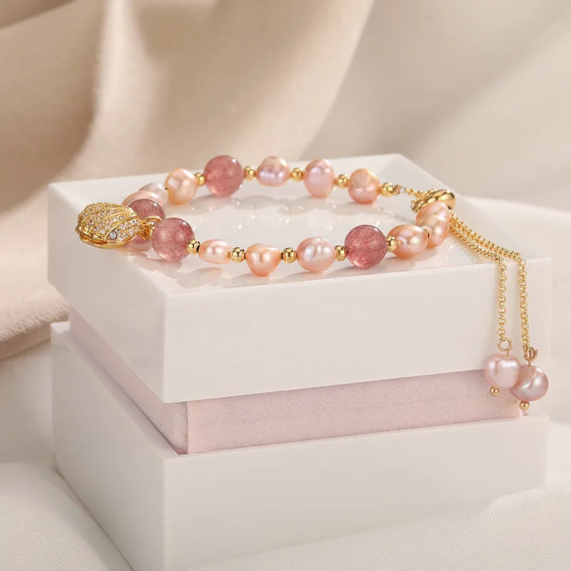 Pink Whisper Shell Bracelet resting on a white gift box, showcasing its pink pearls, quartz beads, and adjustable gold chain.