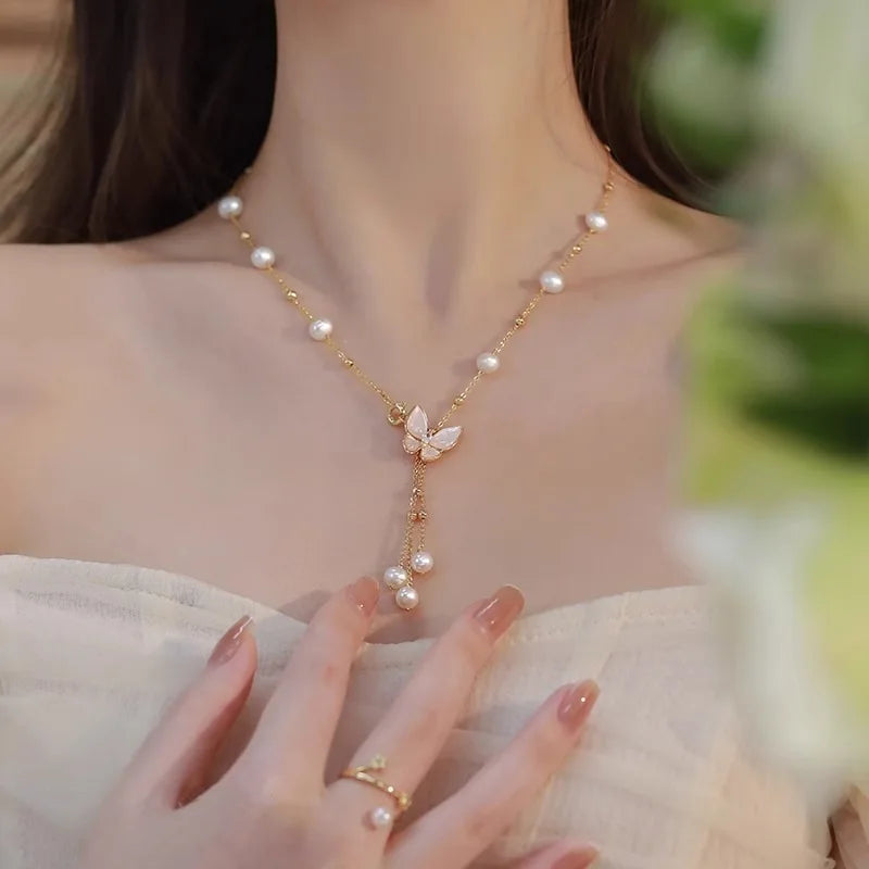 Model wearing Wings of Love Necklace with butterfly and pearl design, showcasing its elegant drape and youthful charm at the neckline.