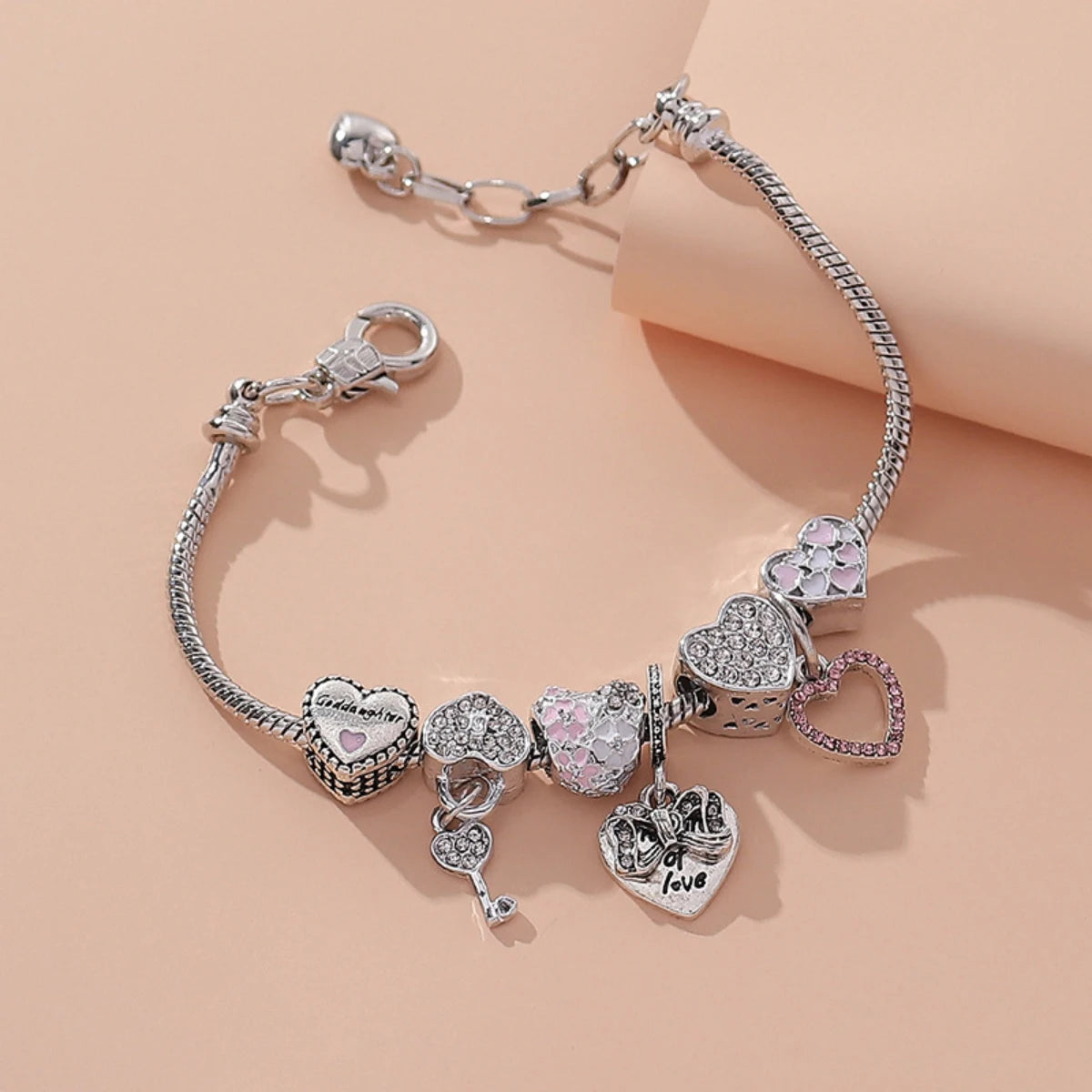 Silver heart-themed charm bracelet with pink and crystal accents, featuring love and key motifs for romantic styling.