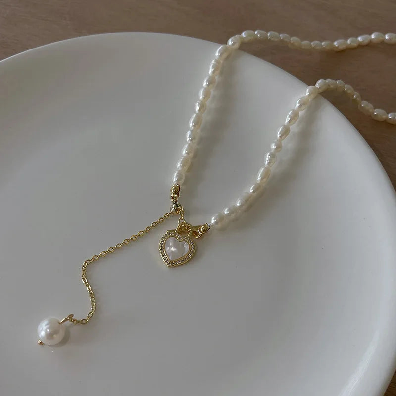 Pearl of My Heart Necklace displayed on a white plate, showing baroque pearls, gold chain, and heart charm with delicate craftsmanship.