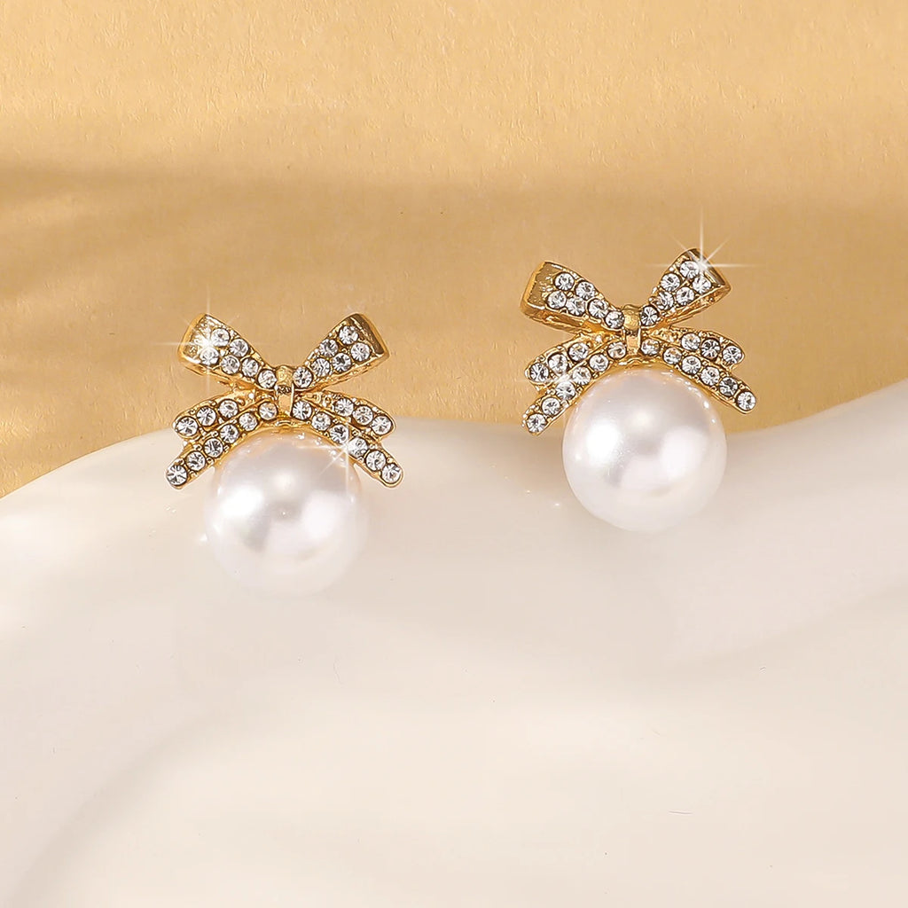 Elegant Silver Bow Diamond & Pearl Stud Earrings displayed on a white and gold background, perfect for weddings, parties, or daily elegance.