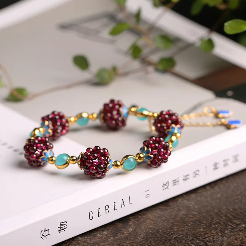 Aurora Stone Bracelet styled on a book, combining garnet clusters, amazonite stones, and 14K gold-filled accents for elegant wear.