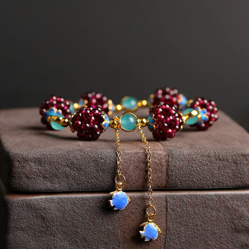 Aurora Stone Bracelet featuring deep garnet clusters and aqua amazonite beads with 14K gold-filled accents, displayed on a brown box.