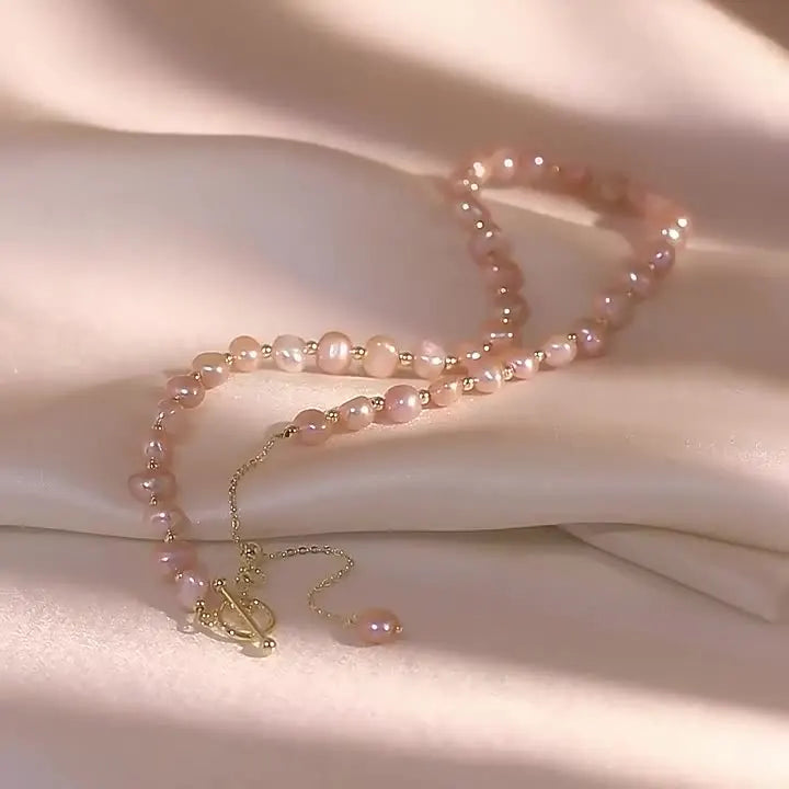 Elegant Pink Baroque Pearl Gold-Filled Necklace with soft luster pearls and gold chain detail, displayed on a blush-toned fabric.