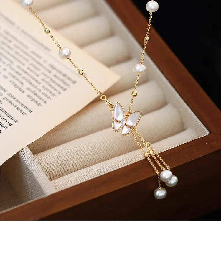 Detailed view of Wings of Love Necklace with butterfly pendant and pearl accents, laid on jewelry box for refined product presentation.