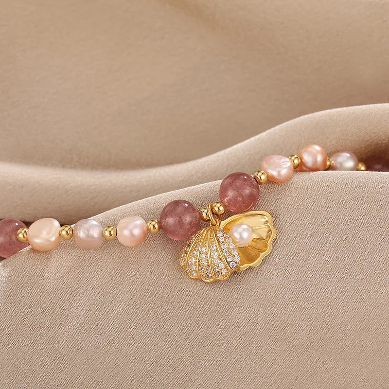 Close-up of Pink Whisper Shell Bracelet highlighting the gold shell charm with pearl and crystal detailing on soft fabric.