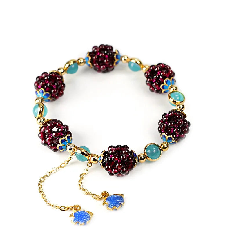 Flat lay of Aurora Stone Bracelet with garnet and amazonite beads, gold-filled chain, and blue enamel fish charms on white background.