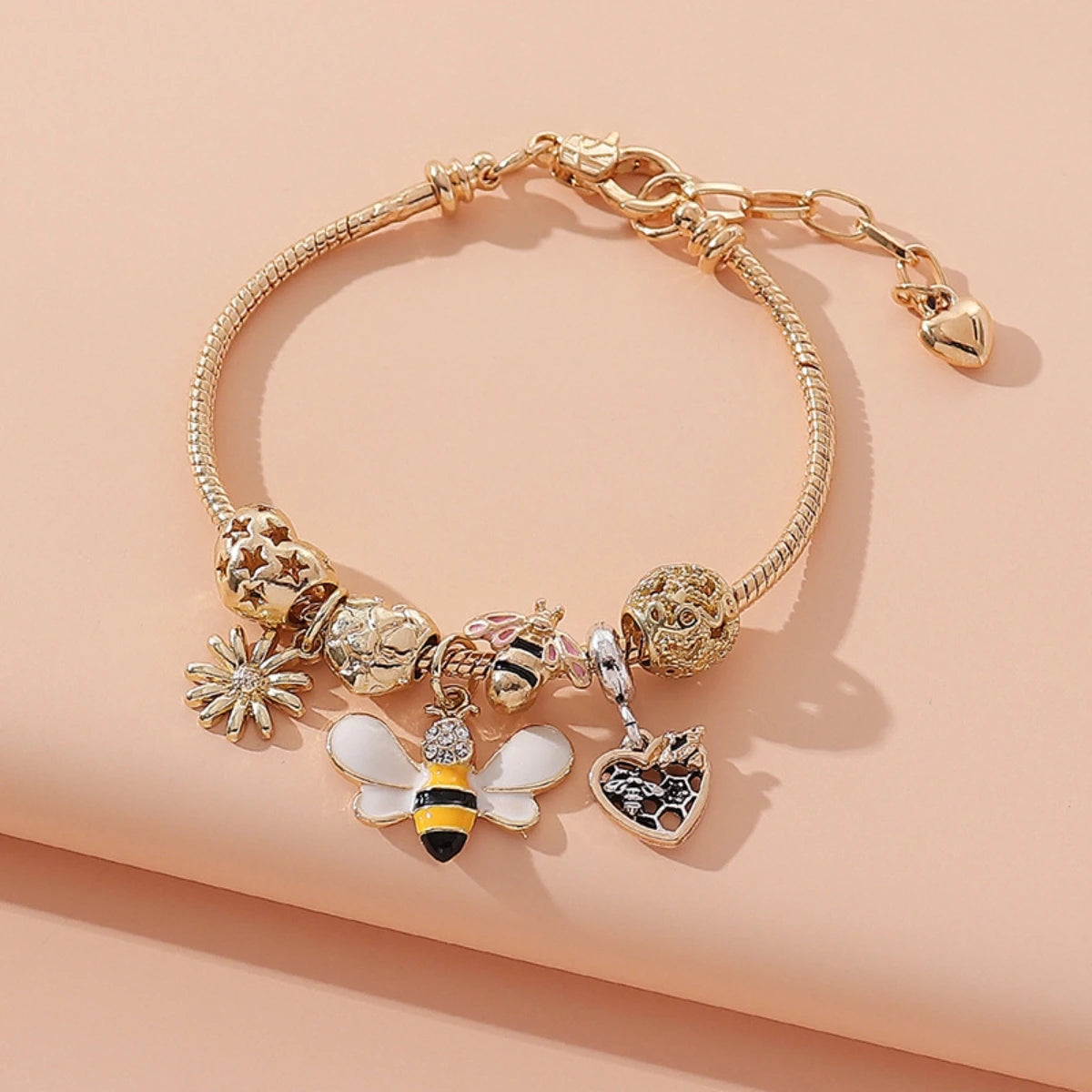 Gold bee-themed charm bracelet with daisy, heart, and honeybee charms, perfect for nature lovers and whimsical fashion.