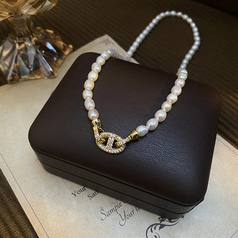 Close-up of Heavenly Glow Choker showcasing pearl beads and a crystal-encrusted gold cross clasp, resting on a black jewelry box.