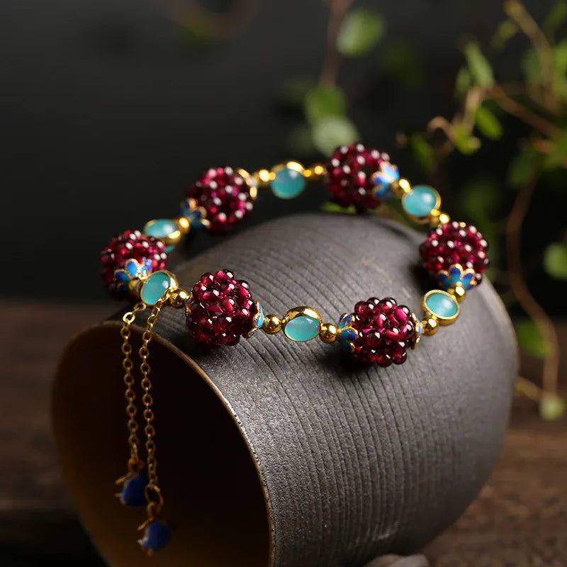 Aurora Stone Bracelet resting on a ceramic cup, highlighting garnet clusters, amazonite stones, and gold-filled detailing.