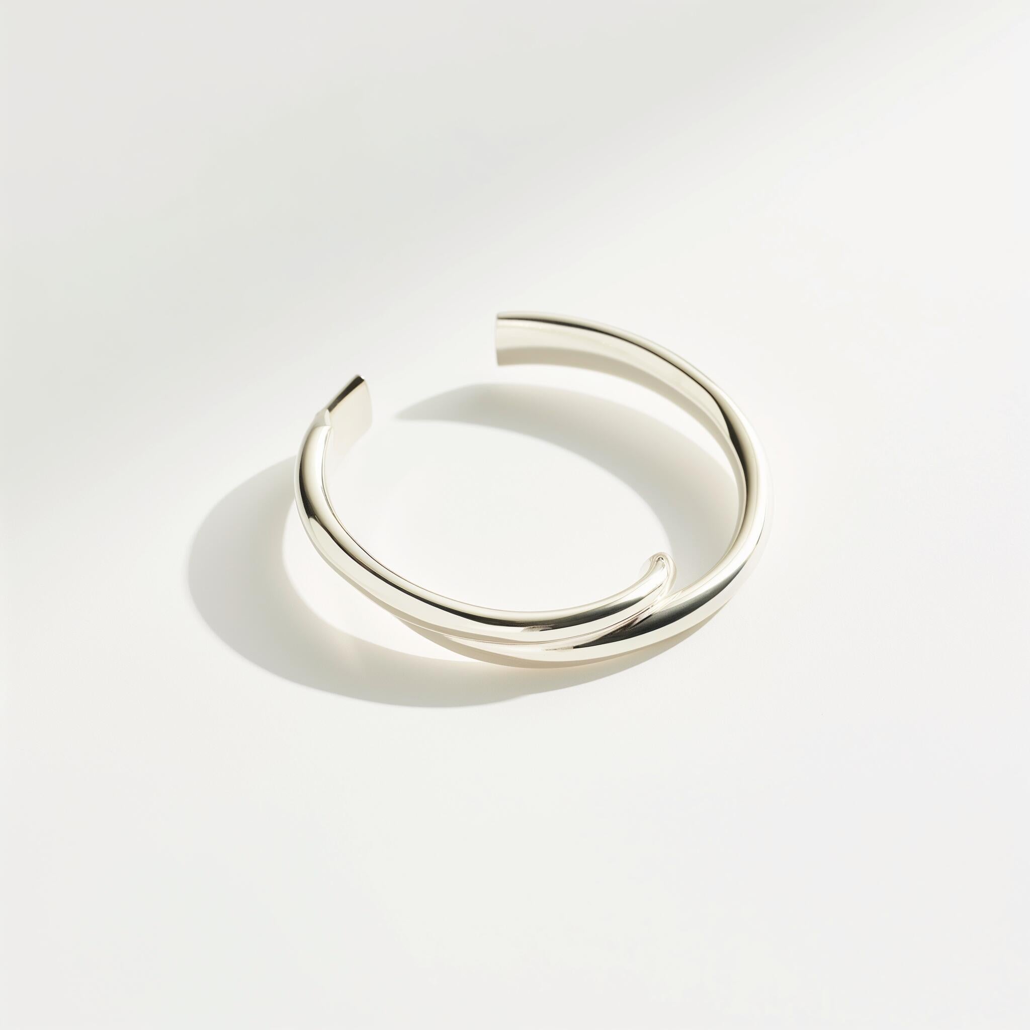 Minimalist silver cuff bracelet with a twisted open design, ideal for modern fashion accessories and contemporary jewelry collections.